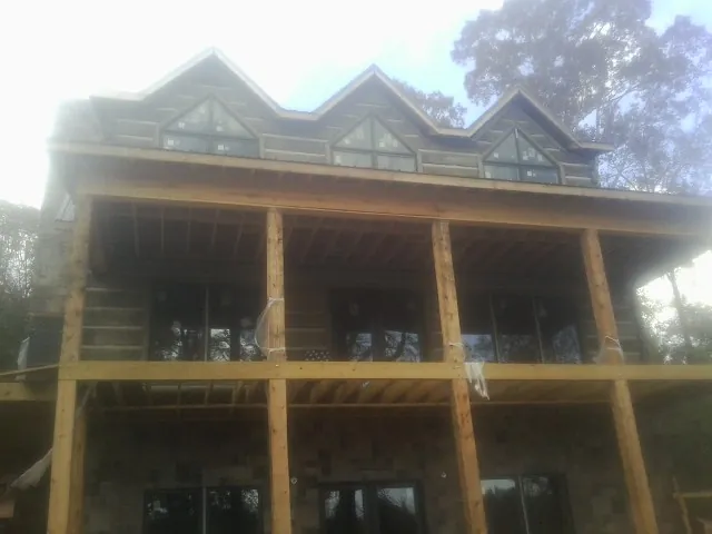 Dormers and porch framing on a large log home under construction — Roof Coating work by our crew in Thaxton
